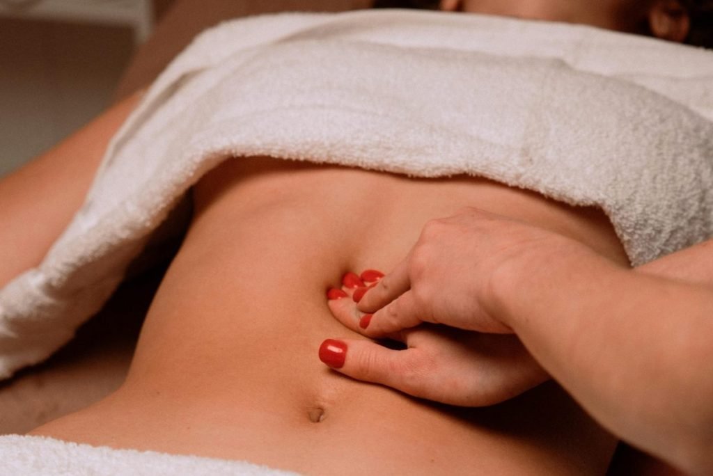 A soothing massage on a woman's abdomen with painted nails, creating a serene spa atmosphere.
